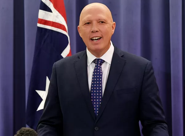 MR Dutton Federal Liberal Party leader standing before the Australian Flag and a blue curtain